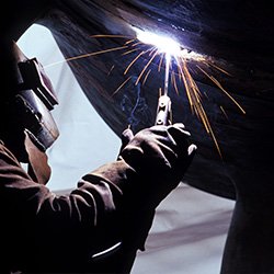 Man Welding Underside Of Pipe